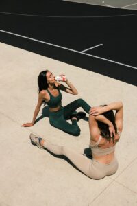 woman in black tank top and white shorts sitting on white concrete floor